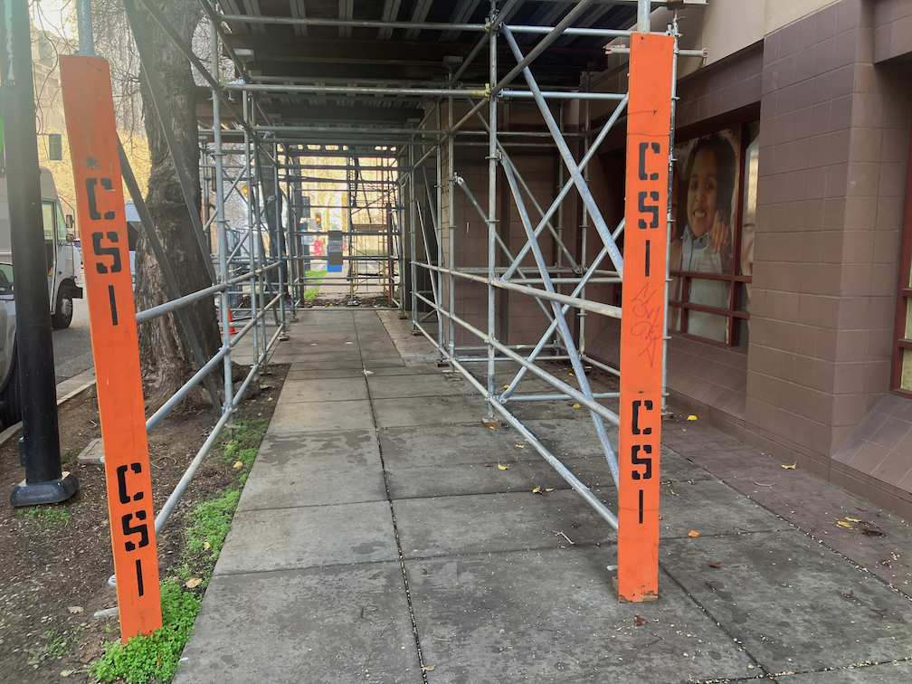 photo of SHRA construction on 6th St, scaffolding as barrier, non-compliant paper sidewalk closed sign